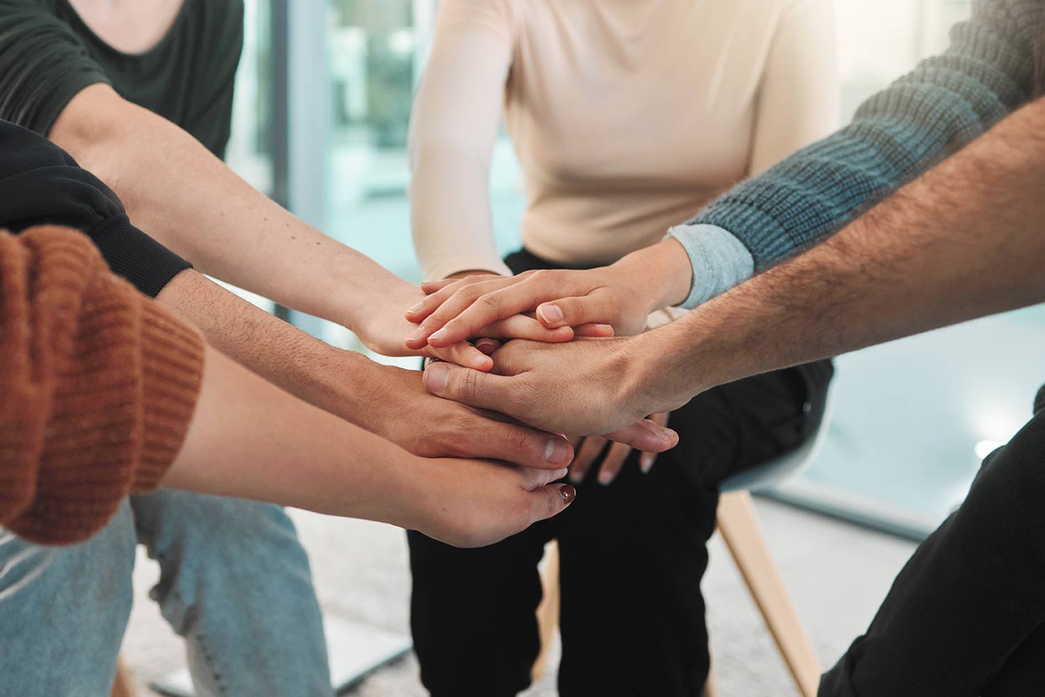 Eine Gruppe von Menschen streckt ihre Hände in die Mitte und legt sie als Gemeinschaft aufeinander